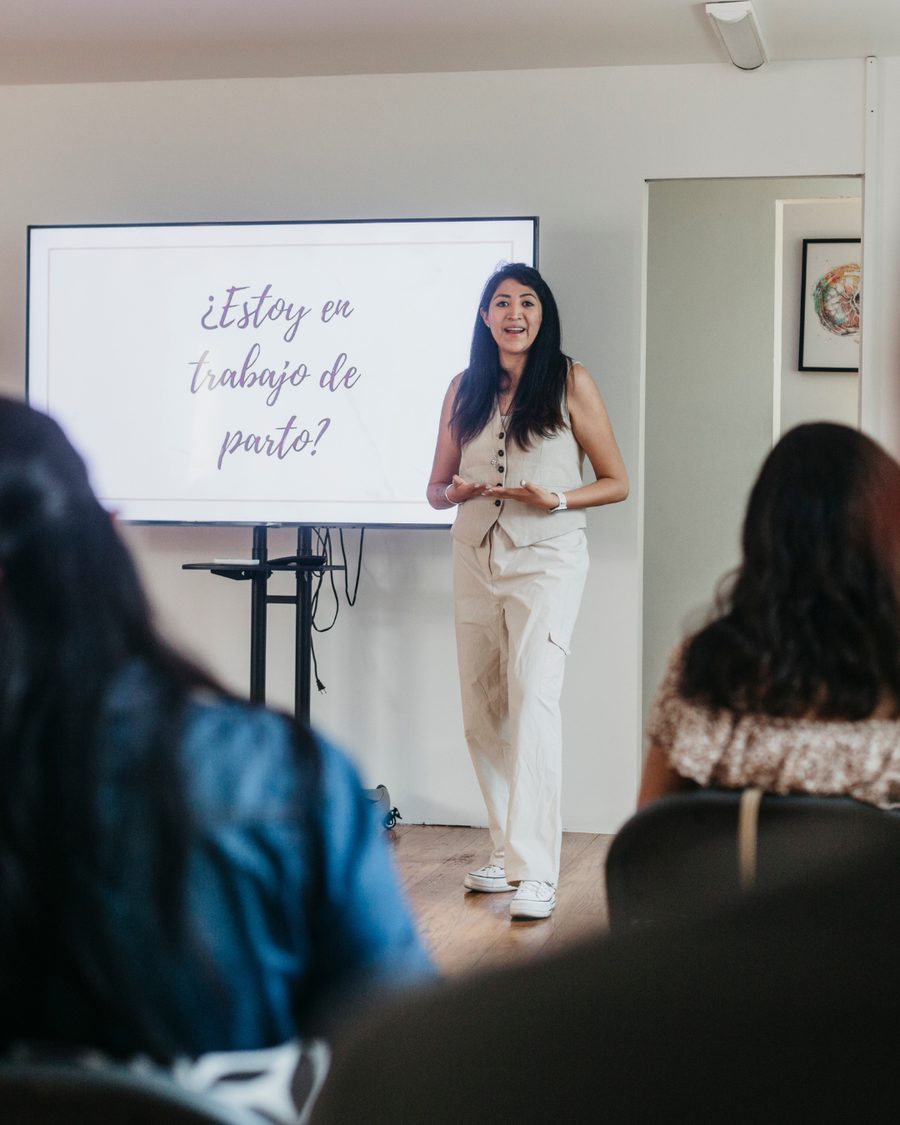 Bea Arce impartiendo el curso prenatal presencial frente a un grupo, junto a la lámina «¿Estoy en trabajo de parto?»