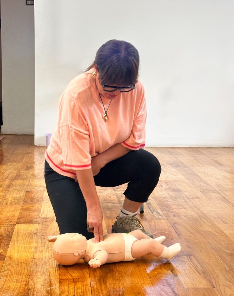 Demostración de reanimación cardiopulmonar sobre un maniquí de bebé durante el taller de primeros auxilios